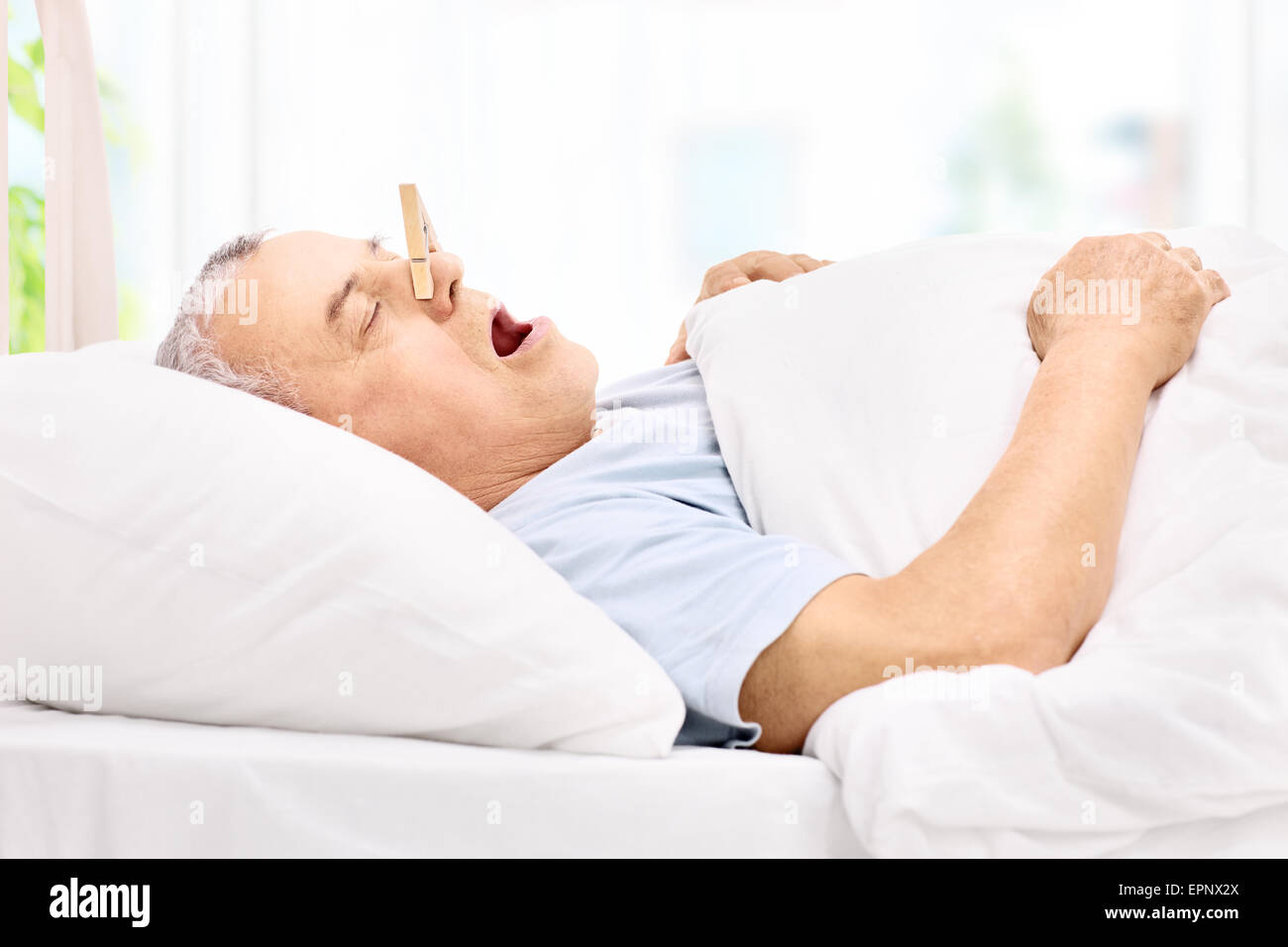 Senior uomo dorme con un clothespin sul suo naso e il russamento a casa Foto Stock