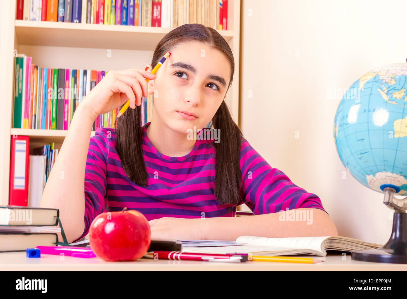 Little Schoolgirl tenendo una matita e di pensare. Foto Stock