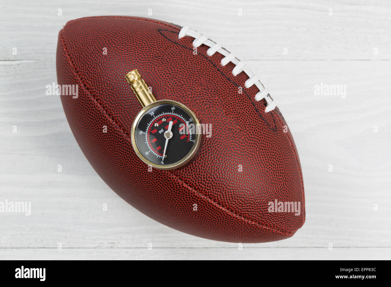 Close up d'America football con aria il manometro sulla parte superiore della sfera con rustico in legno di colore bianco al di sotto. Foto Stock