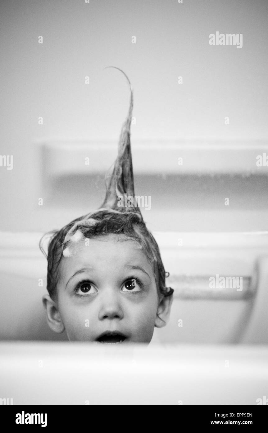 La ragazza (3-4 anni) prendere un bagno e guardando il dentato per capelli. Foto Stock