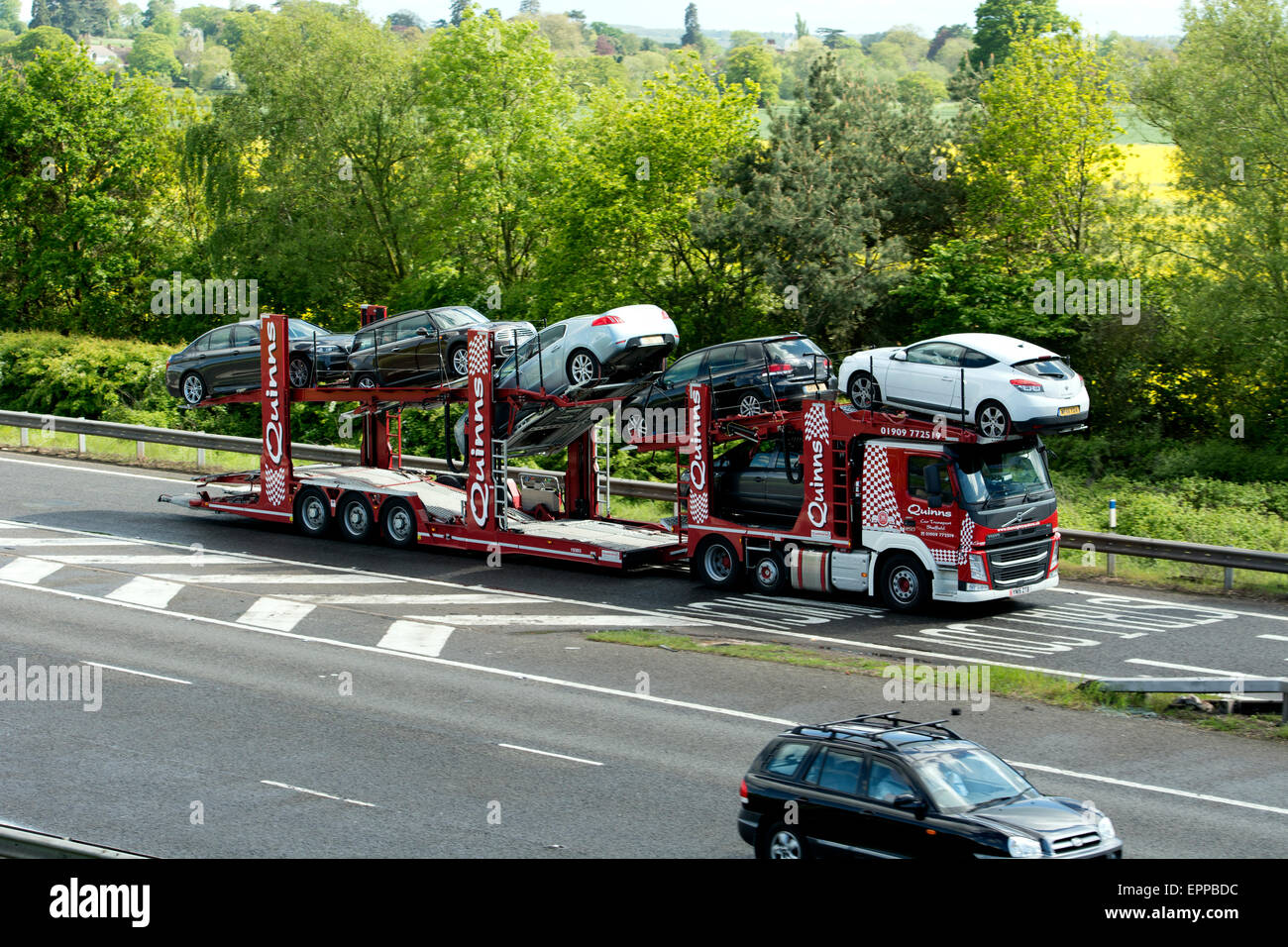 Quinns transporter camion che trasportano auto usate di lasciare l'autostrada M40, Warwickshire, Regno Unito Foto Stock