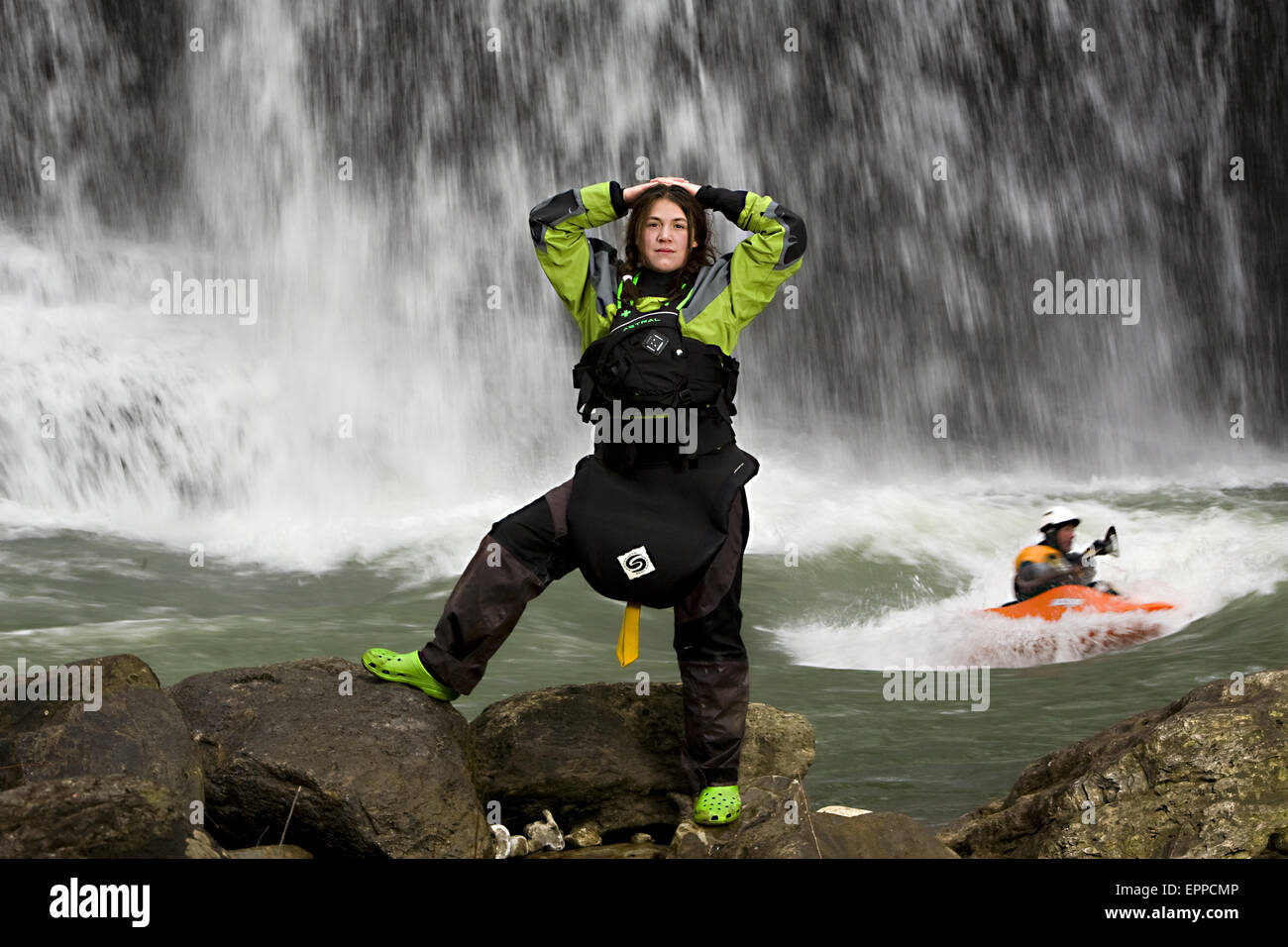 Ritratto di una donna attraente kayaker di fronte ad una cascata e foro di gioco con un altro kayaker. Foto Stock