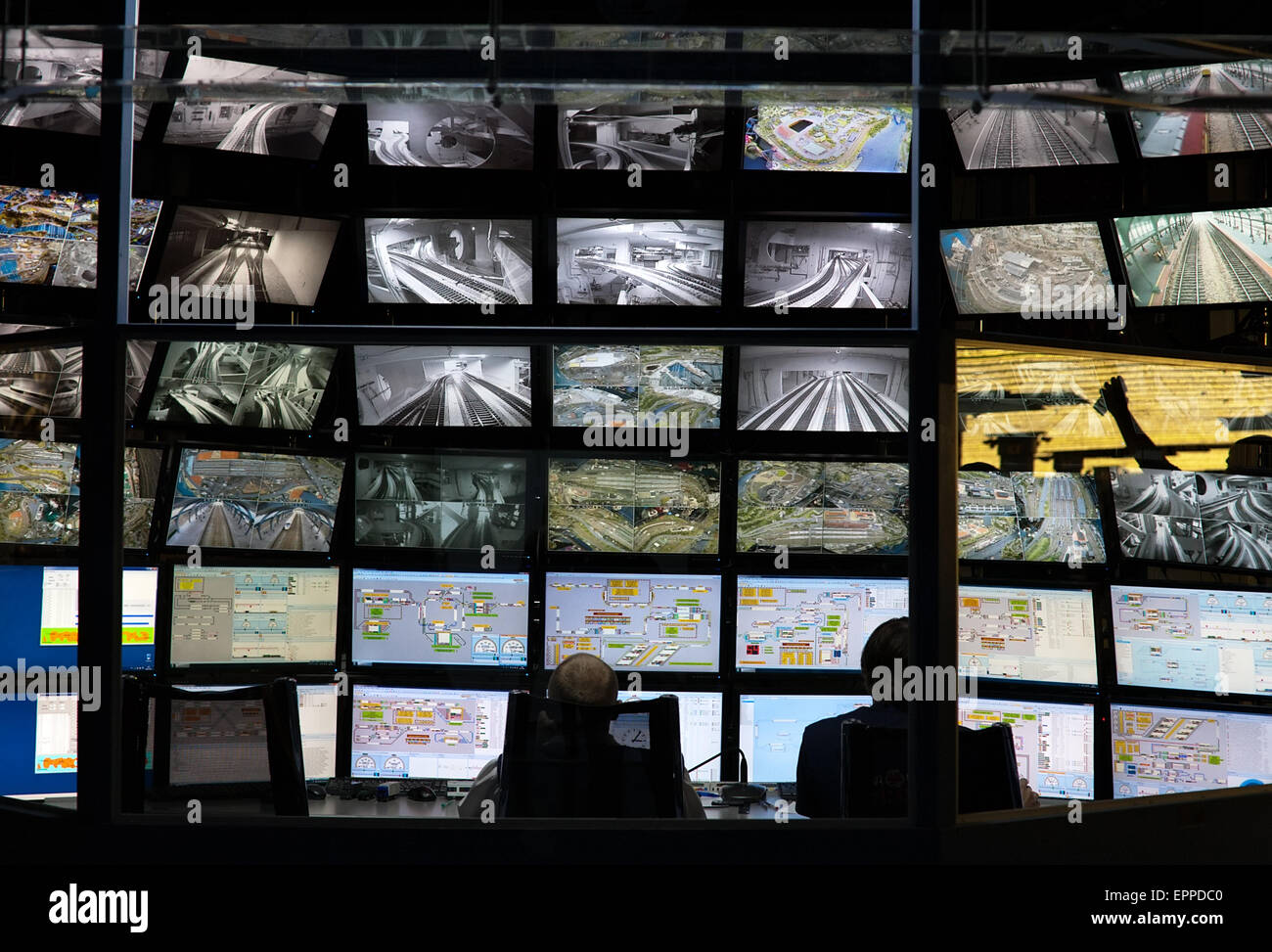 Monitoraggio della sicurezza della console di controllo camera con una parete di schermi e due lavoratori silhouette posteriore Foto Stock
