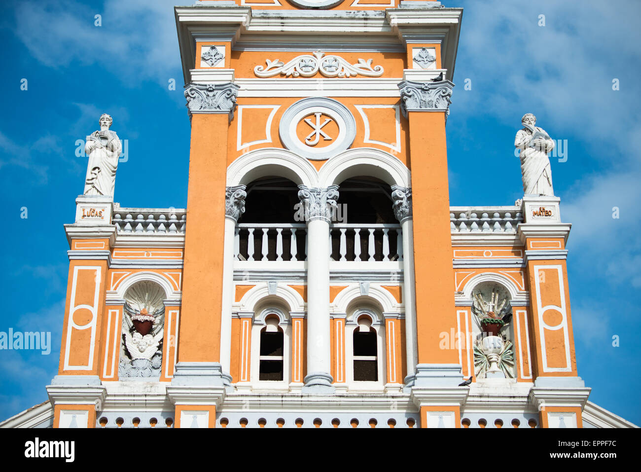 Iglesia de Xalteva Campanile Granada Nicaragua // GRANADA, Nicaragua — il caratteristico campanile di Iglesia de Xalteva sorge sopra la storica città coloniale di Granada. Questa chiesa cattolica in stile barocco, conosciuta per la sua suggestiva facciata arancione e bianca, è una delle più antiche strutture religiose della regione. Iglesia de Xalteva è un importante punto di riferimento nel quartiere Xalteva di Granada, un'area che un tempo era il centro di una comunità indigena prima della colonizzazione spagnola. Gli elementi architettonici della chiesa mostrano la fusione di influenze europee e locali tipiche del re coloniale Foto Stock