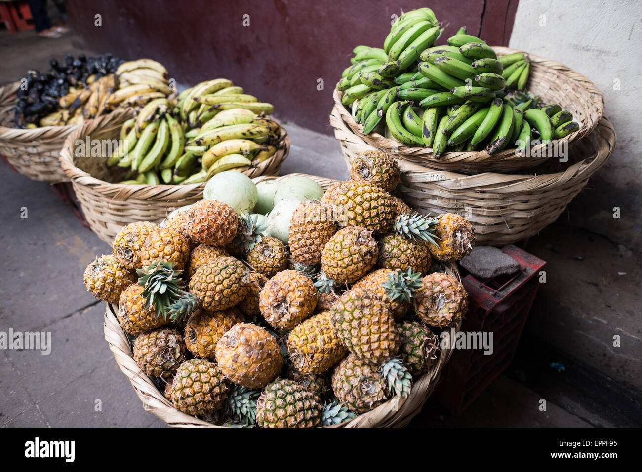 GRANADA, Nicaragua - al Mercado Municipal sono esposti ananas e banane fresche, due dei principali prodotti agricoli del Nicaragua. Questi frutti tropicali rappresentano sia le tradizioni agricole locali che il patrimonio agricolo del paese. Il mercato funge da collegamento diretto tra i produttori regionali di frutta e i consumatori urbani. Foto Stock