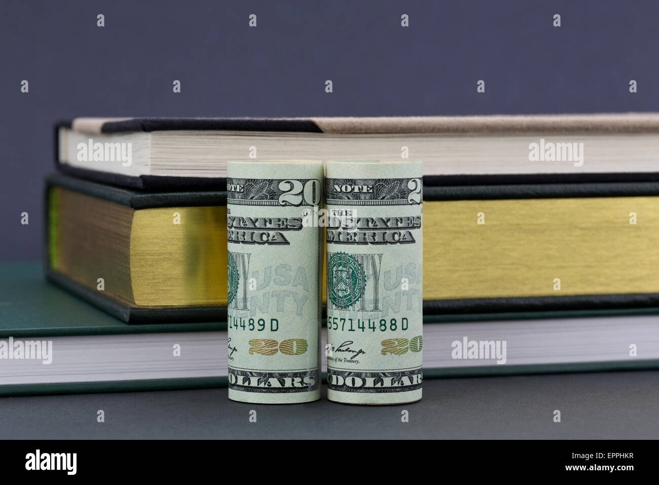 Costi e finanziamento delle domande di educazione riflessa dalla moneta americana posta con libri su sfondo grigio. Foto Stock
