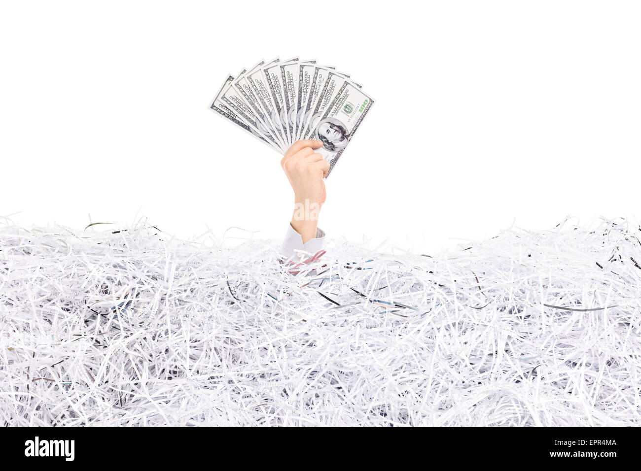 Studio shot di una mano di un uomo bloccato in una pila di carta tagliuzzata una catasta di denaro al di sopra della superficie Foto Stock