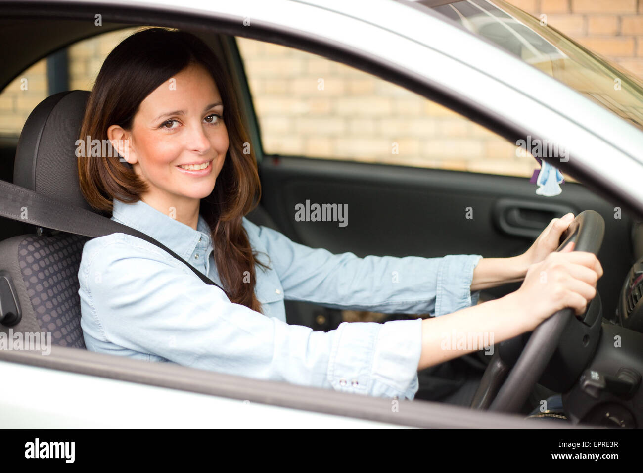 Giovane donna alla guida la sua auto con il suo allacciata la cintura di sicurezza Foto Stock