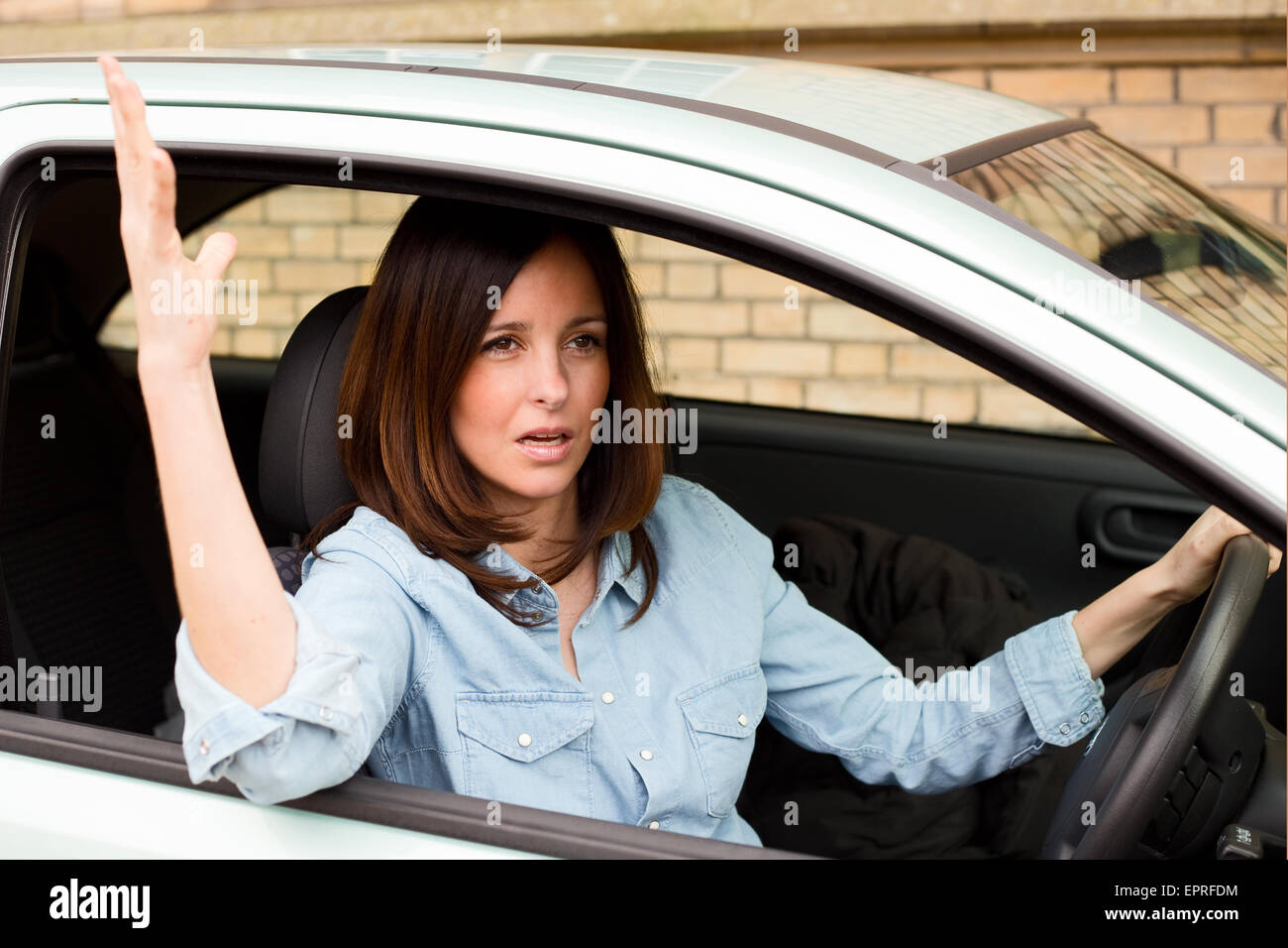 Giovane donna conducente agitando la mano infastidito. Foto Stock