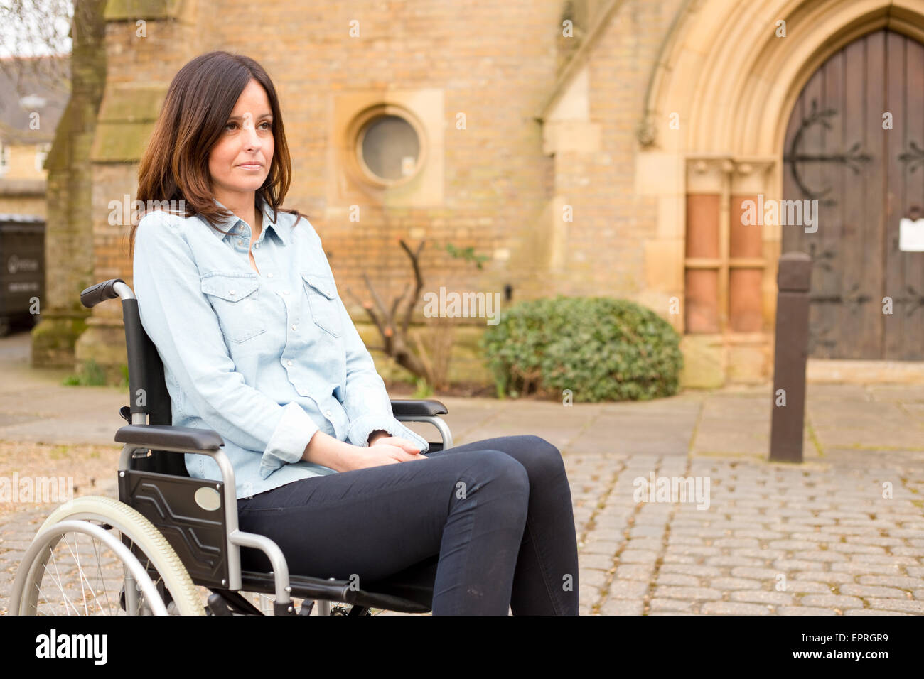 Una giovane donna in una sedia a rotelle cercando triste Foto Stock