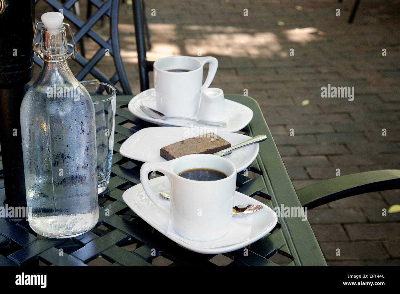 Caffè, Brownie e bottiglia di acqua minerale sul tavolo del patio al Cafe, Dundas, Ontario, Canada Foto Stock