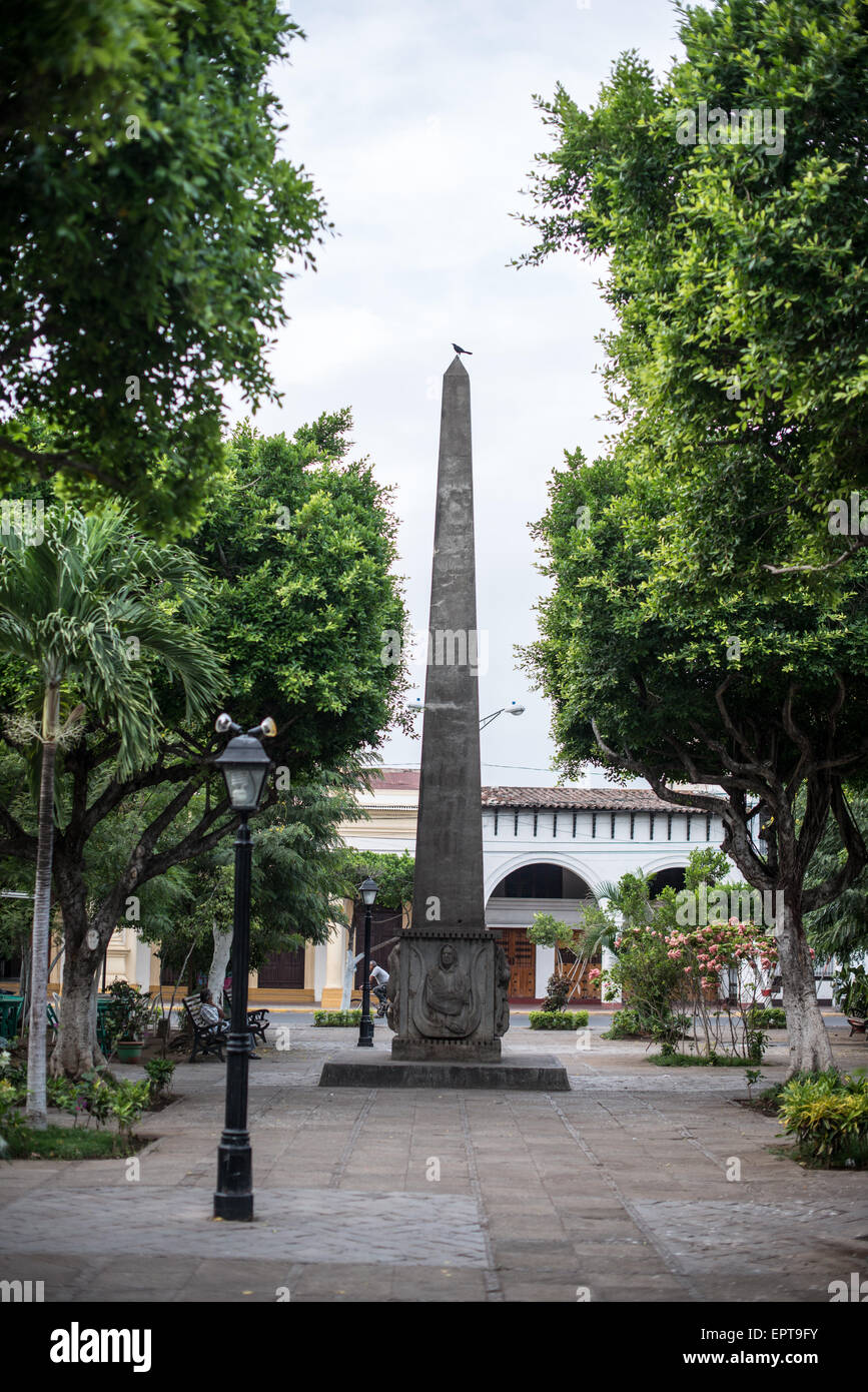 Rubén Darío Monument Parque Central Granada Nicaragua // GRANADA, Nicaragua — Un monumento in pietra obelisco in onore del famoso poeta nicaraguense Rubén Darío (nato Félix Rubén García Sarmiento) nel Parque Central della città. Il monumento fu installato nel 1966 per commemorare il 50° anniversario della morte di Darío. Considerato il padre del movimento letterario ispano-americano noto come Modernismo, Darío è ampiamente considerato come una delle figure letterarie più influenti dell'America Latina. Il Parque Central è la piazza principale e il cuore storico di Granada, una delle città coloniali più antiche del Nicaragua. La plaza I. Foto Stock