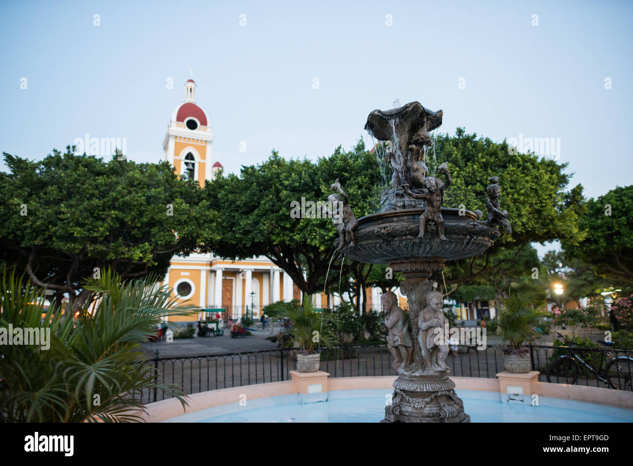 Parque Central Fountain Cattedrale di Granada Nicaragua // GRANADA, Nicaragua - Una fontana si trova nel centro del Parque Central, la piazza principale e il cuore storico di Granada. La Cattedrale di Granada è visibile sullo sfondo, parzialmente oscurata dagli alberi. Parque Central è un luogo di ritrovo per la gente del posto e i visitatori di questa città coloniale, fondata nel 1524 ed è una delle più antiche città europee insediate nelle Americhe. La cattedrale, ufficialmente conosciuta come cattedrale di Granada o la Catedral de Granada, è una struttura neoclassica distintiva che domina l'est Foto Stock Parque Central Fountain Cattedrale di Granada Nicaragua // GRANADA, Nicaragua - Una fontana si trova nel centro del Parque Central, la piazza principale e il cuore storico di Granada. La Cattedrale di Granada è visibile sullo sfondo, parzialmente oscurata dagli alberi. Parque Central è un luogo di ritrovo per la gente del posto e i visitatori di questa città coloniale, fondata nel 1524 ed è una delle più antiche città europee insediate nelle Americhe. La cattedrale, ufficialmente conosciuta come cattedrale di Granada o la Catedral de Granada, è una struttura neoclassica distintiva che domina l'est Foto Stock