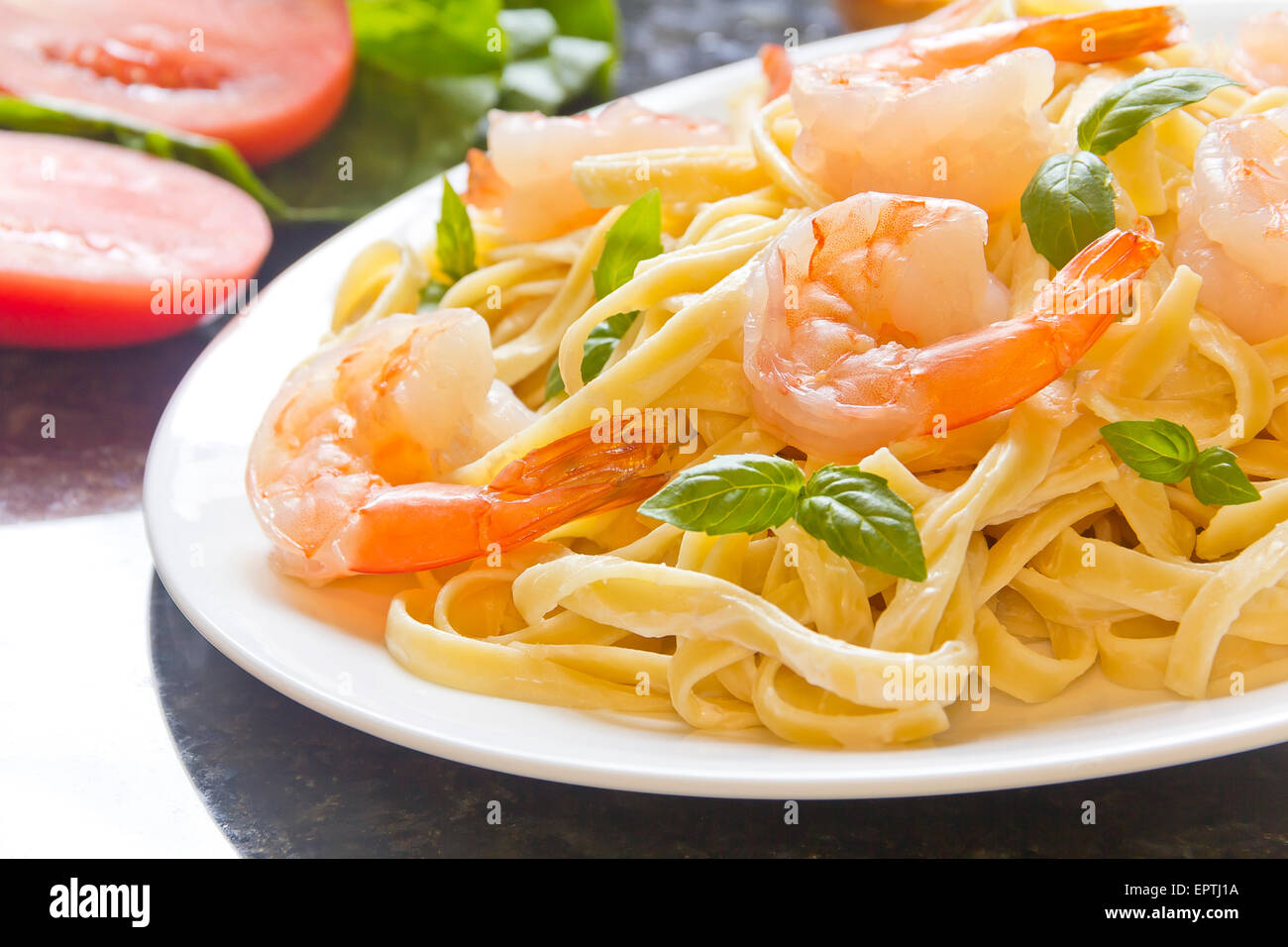 Shrimp Fettuccini Alfredo con foglie di basilico fresco nella disposizione di fantasia Foto Stock