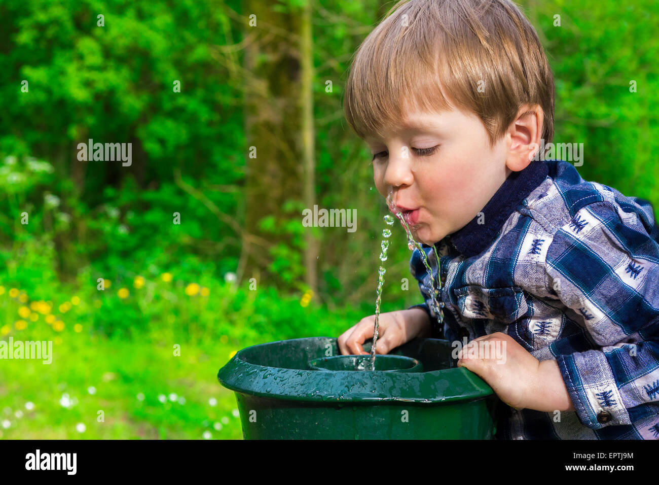 Carino piccolo ragazzo di bere da una fontana Foto Stock