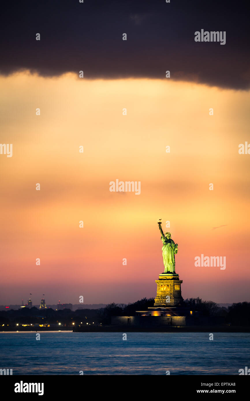 Statua della Libertà sotto una drammatica la luce del tramonto visto da Brooklyn, New York Foto Stock