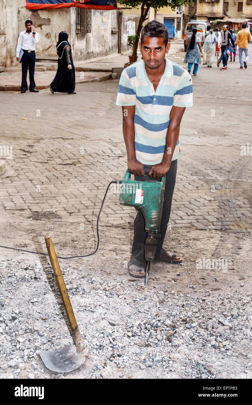 Mumbai India,Dharavi,Shahu Nagar Road,slum,uomo uomo maschio,martello elettrico,lavoro su strada,riparazione,lavoro,lavoro,India150228037 Foto Stock