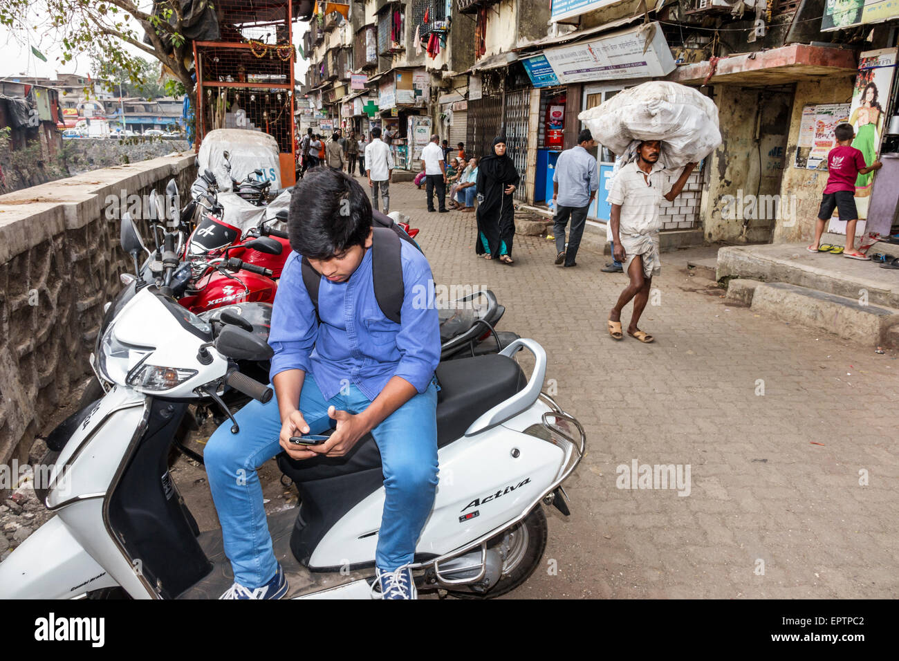 Mumbai India,Dharavi,Shahu Nagar Road,teen teen teenager ragazzi maschi ragazzi bambini bambini cercando,cercando di leggere messaggi di testo, sma Foto Stock