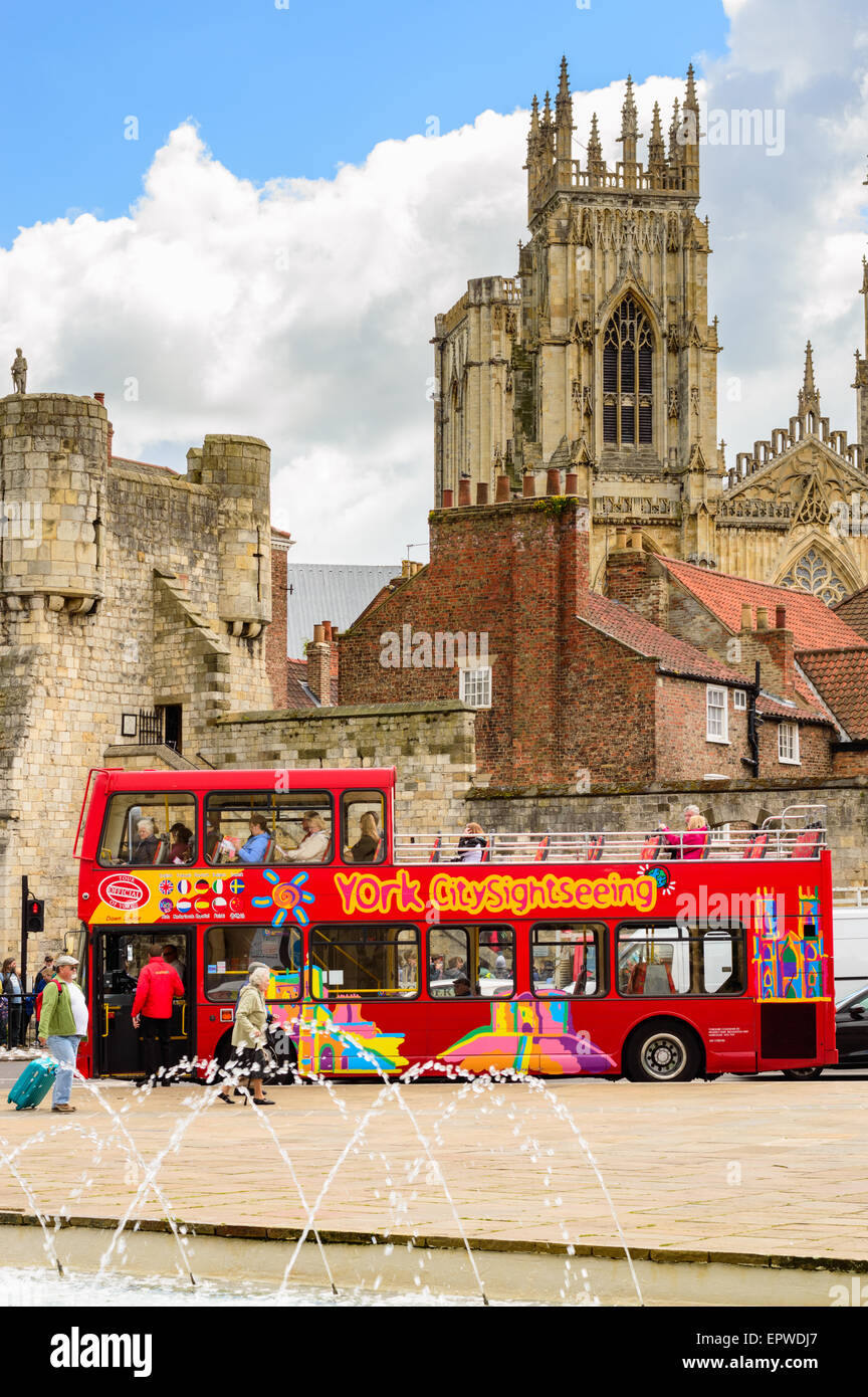 Un rosso sightseeing bus tour di prelevare i clienti - con York Minster in background. In York, Inghilterra. Foto Stock