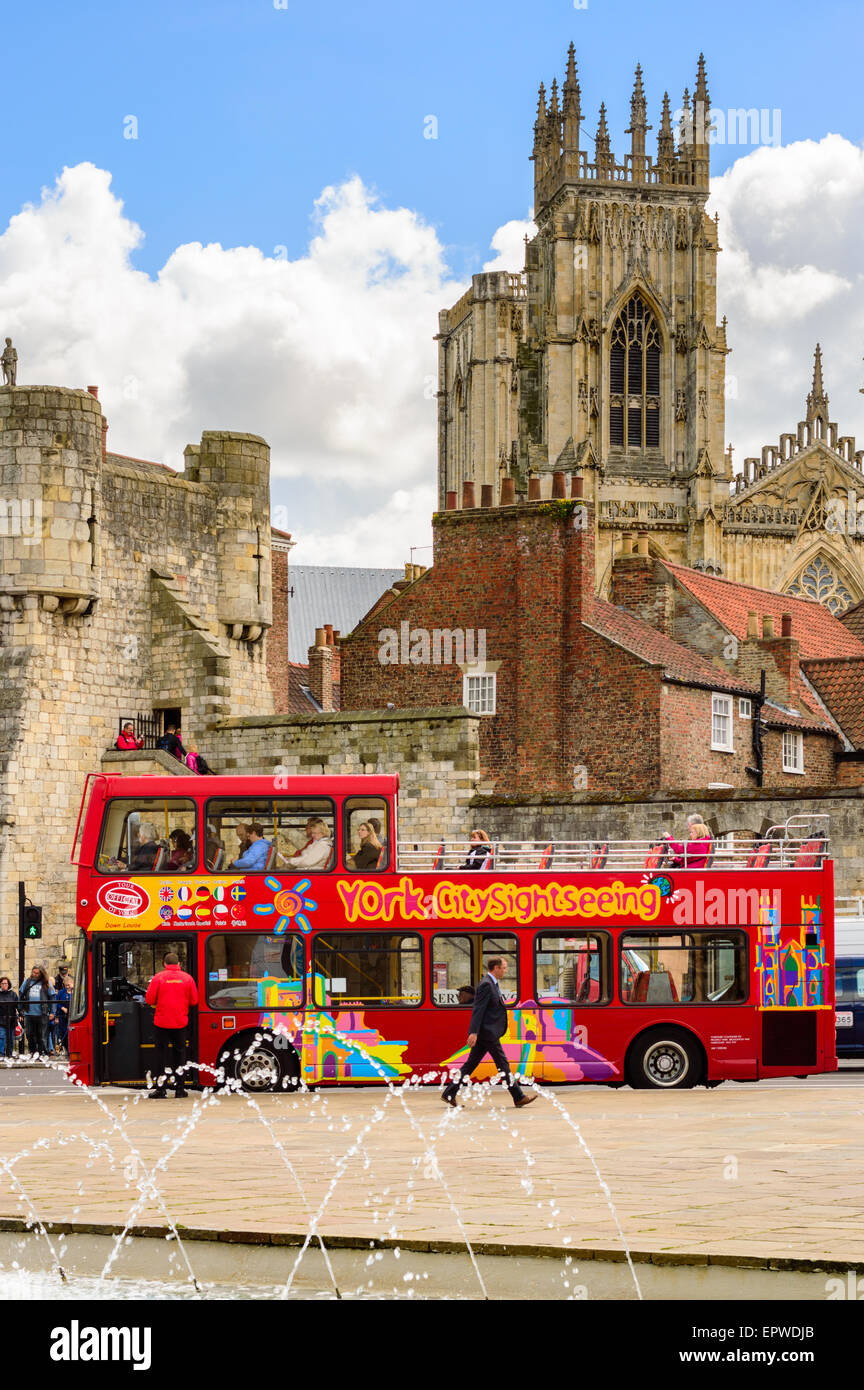 Un rosso sightseeing bus tour di prelevare i clienti - con York Minster in background. In York, Inghilterra. Foto Stock