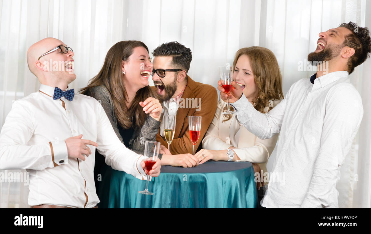 Gli amici di ridere ilarità in un bar, tenendo i bicchieri di vino Foto Stock