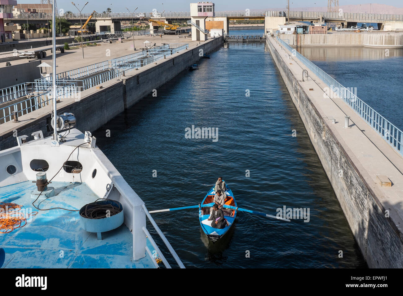 Barca a remi con equipaggi da persone locali di vendita doni turistica entra le serrature a Esna sotto la prua di una crociera sul Nilo nave, Egitto Foto Stock