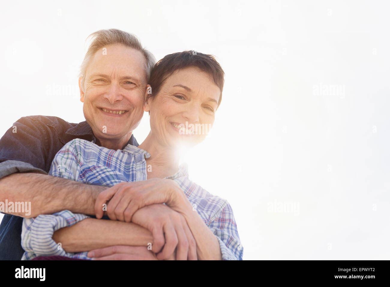 Ritratto di sorridente coppia senior abbracciando nella luce solare Foto Stock