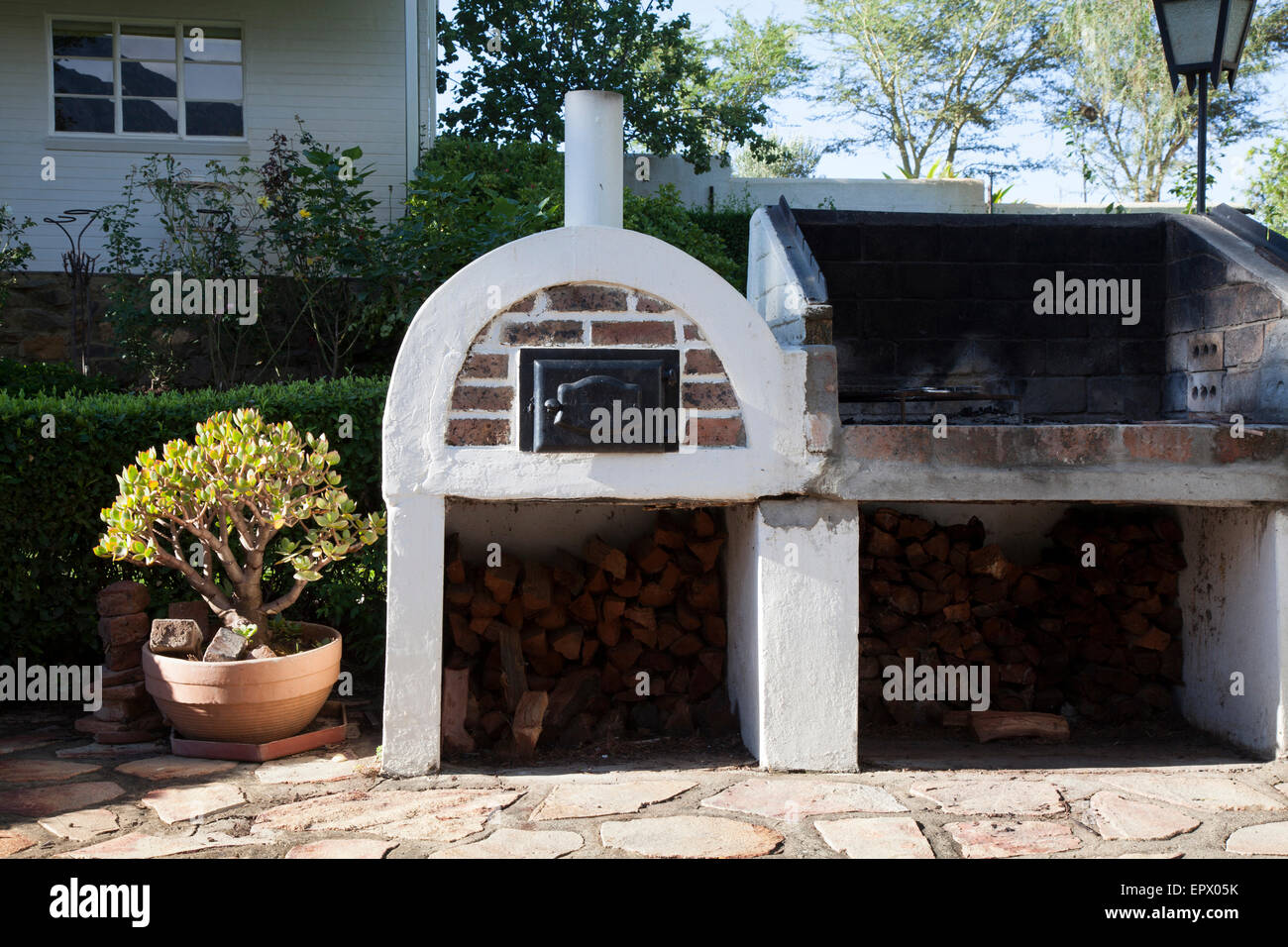 Bianco e mattoni faccia a vista per esterno forno del pane e aprire un barbeque pit con legno in South African home Foto Stock