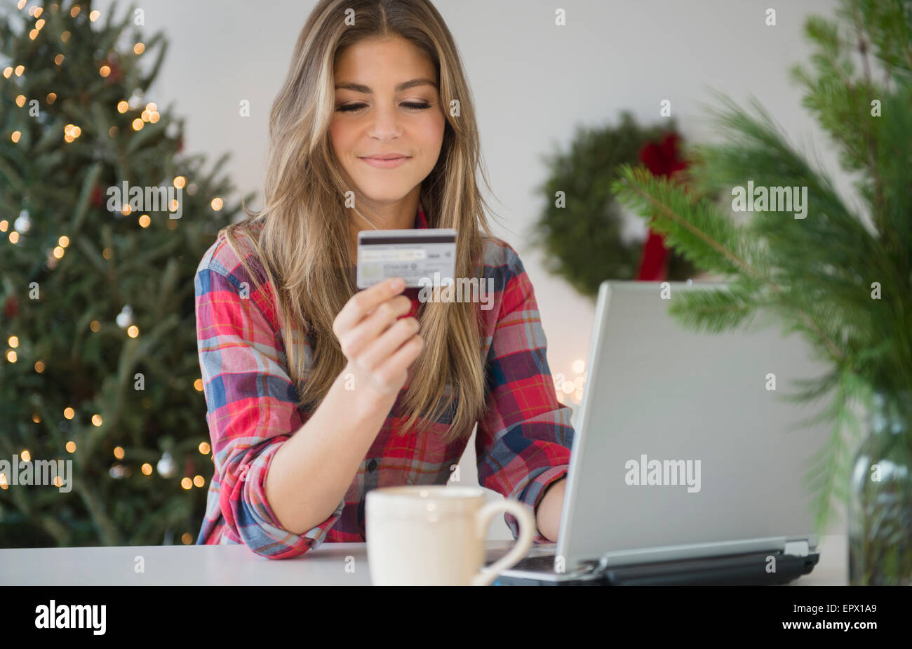 Giovane donna utilizzando la carta di credito durante lo shopping online Foto Stock