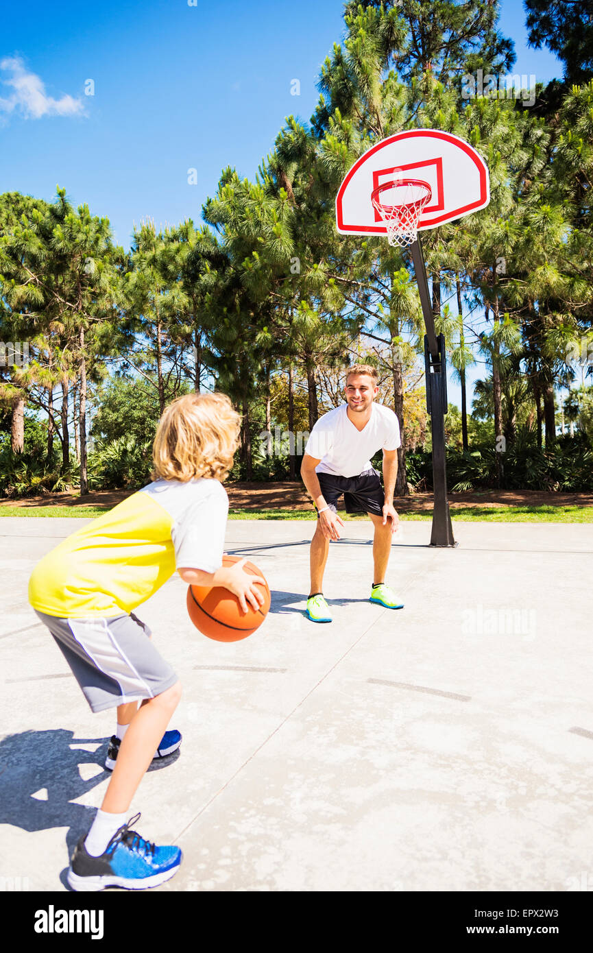 Ragazzo (8-9) giocare a basket con suo fratello Foto Stock