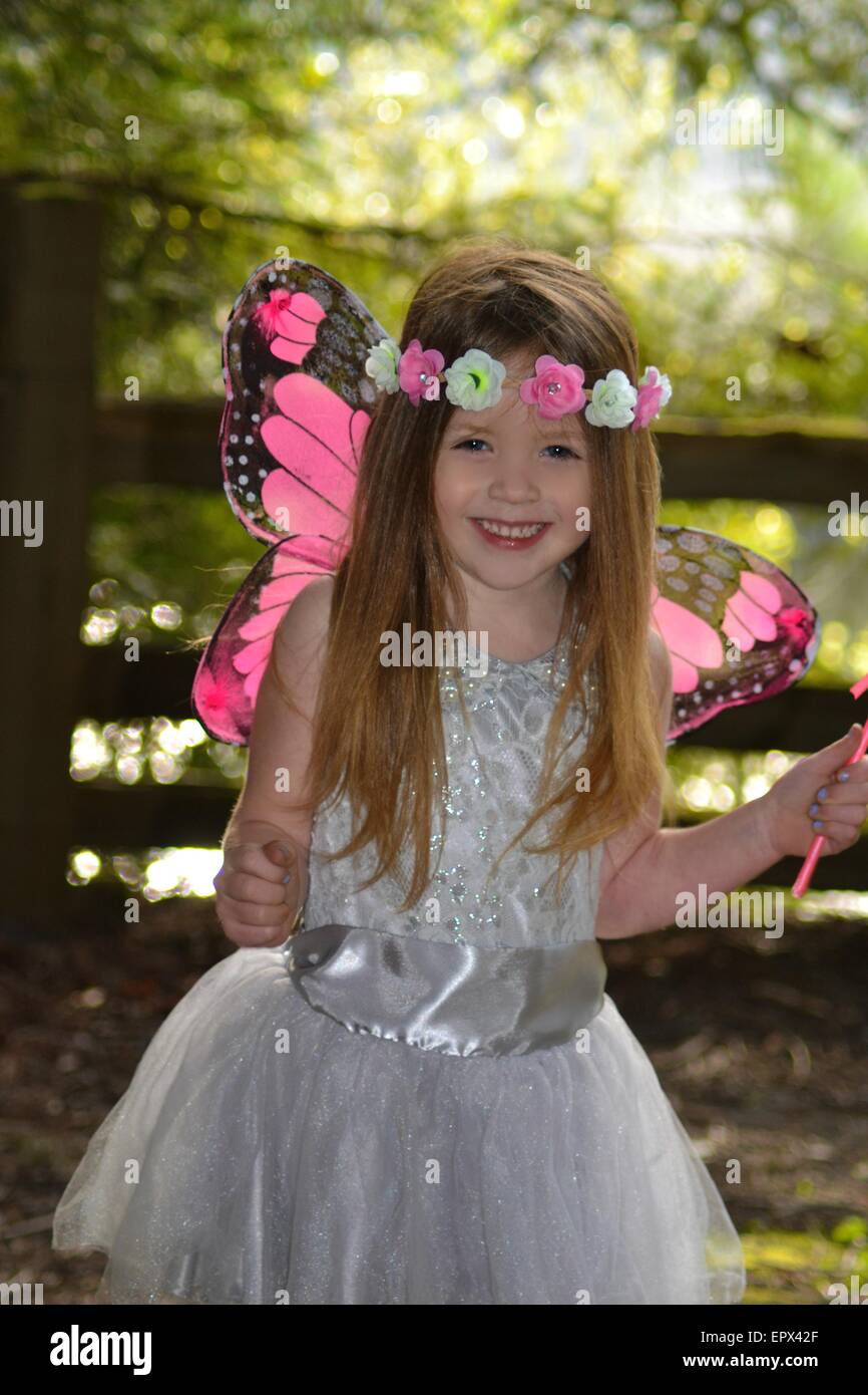 Giovane ragazza bionda con abbastanza occhi blu con una rosa e bianco archetto fiorito e rosa e nero ali di fata. Foto Stock