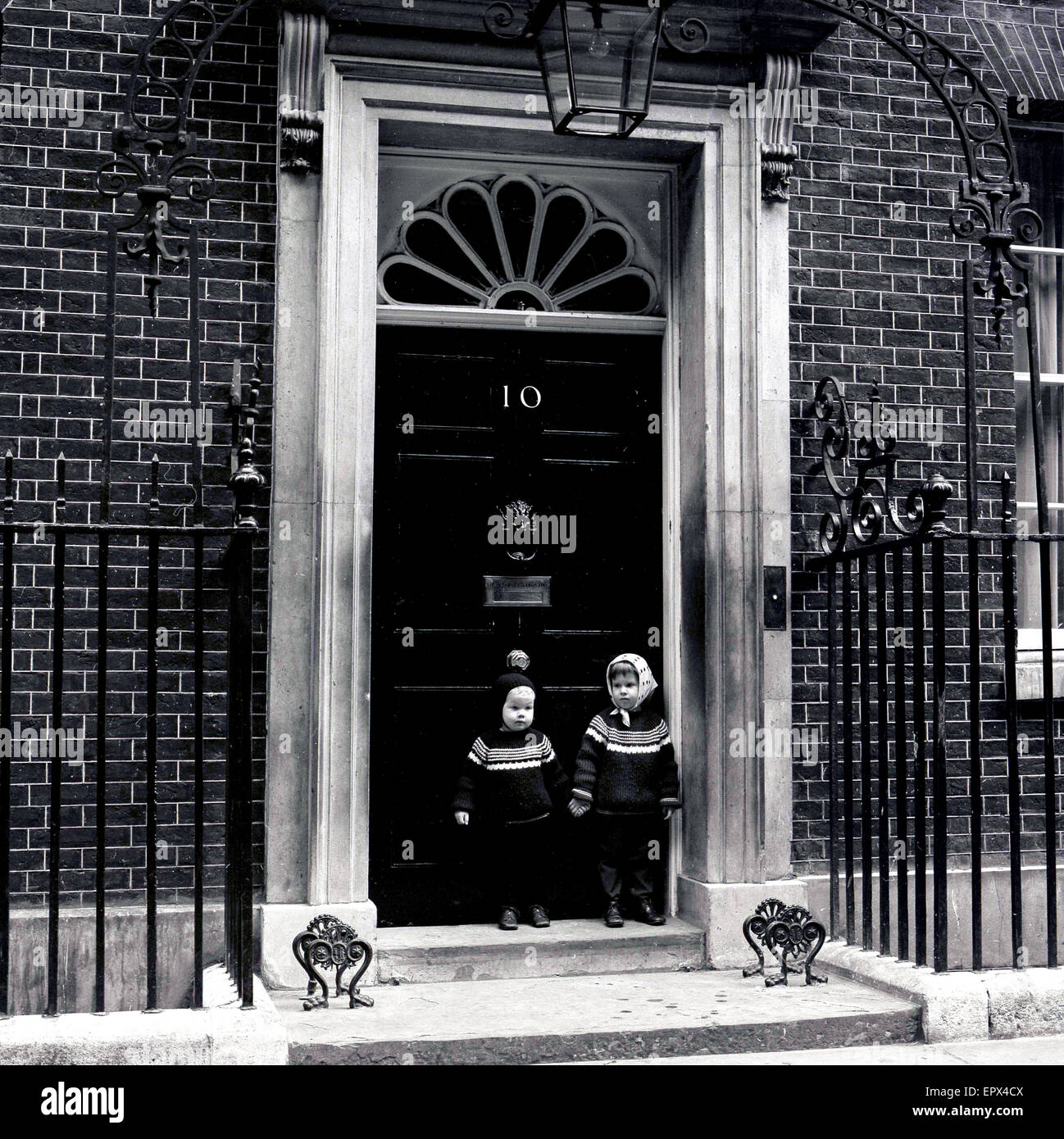 Degli anni Cinquanta, storico, due bambini piccoli in piedi, tenendo le mani al di fuori dell'entrata al n. 10 di Downing Street, Westminster, London, residenza ufficiale del Primo Ministro britannico. Foto Stock