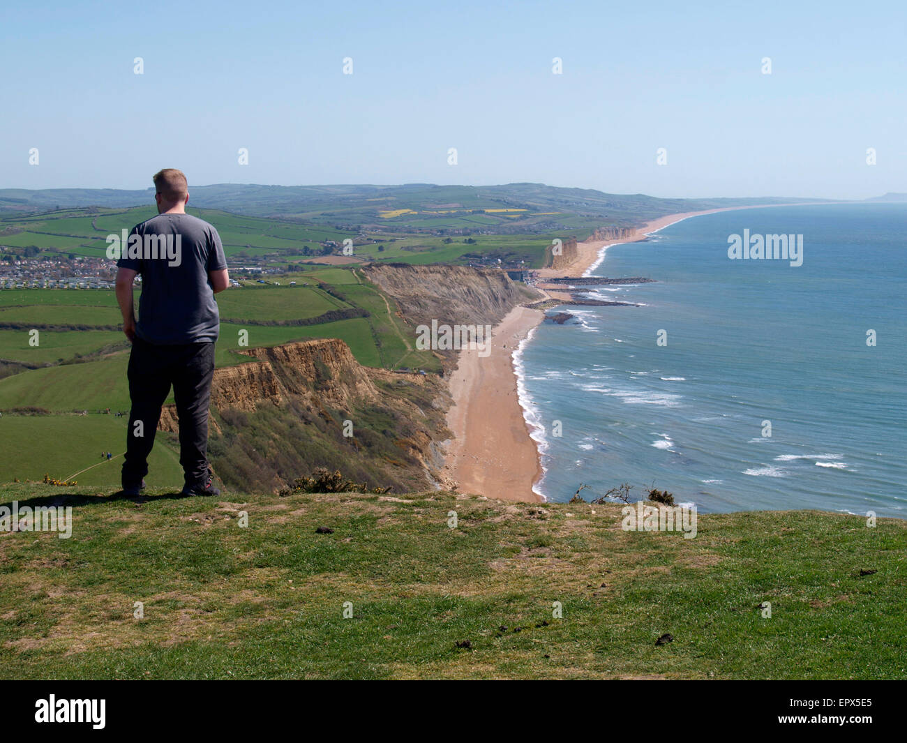 Uomo in piedi in cima Thorncombe Beacon Hill vicino Eype guardando verso il West Bay, Dorset, Regno Unito Foto Stock