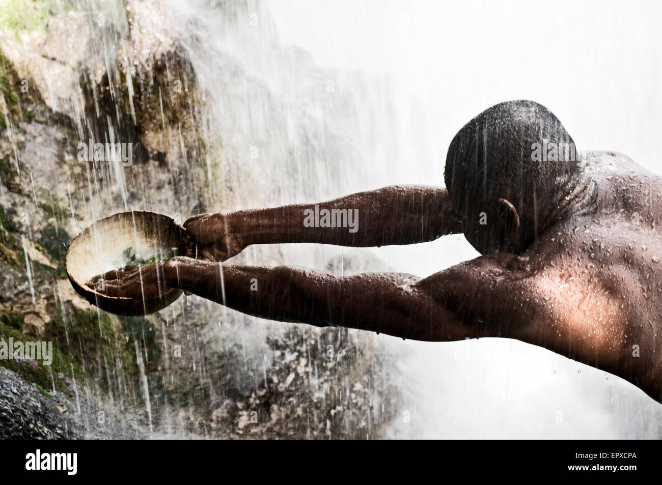 Voodoo Festival di Saut d'Eau, Haiti. Un uomo raccoglie l'acqua che cade dalla cascata di purificare la sua. In questa festa del voodoo Foto Stock