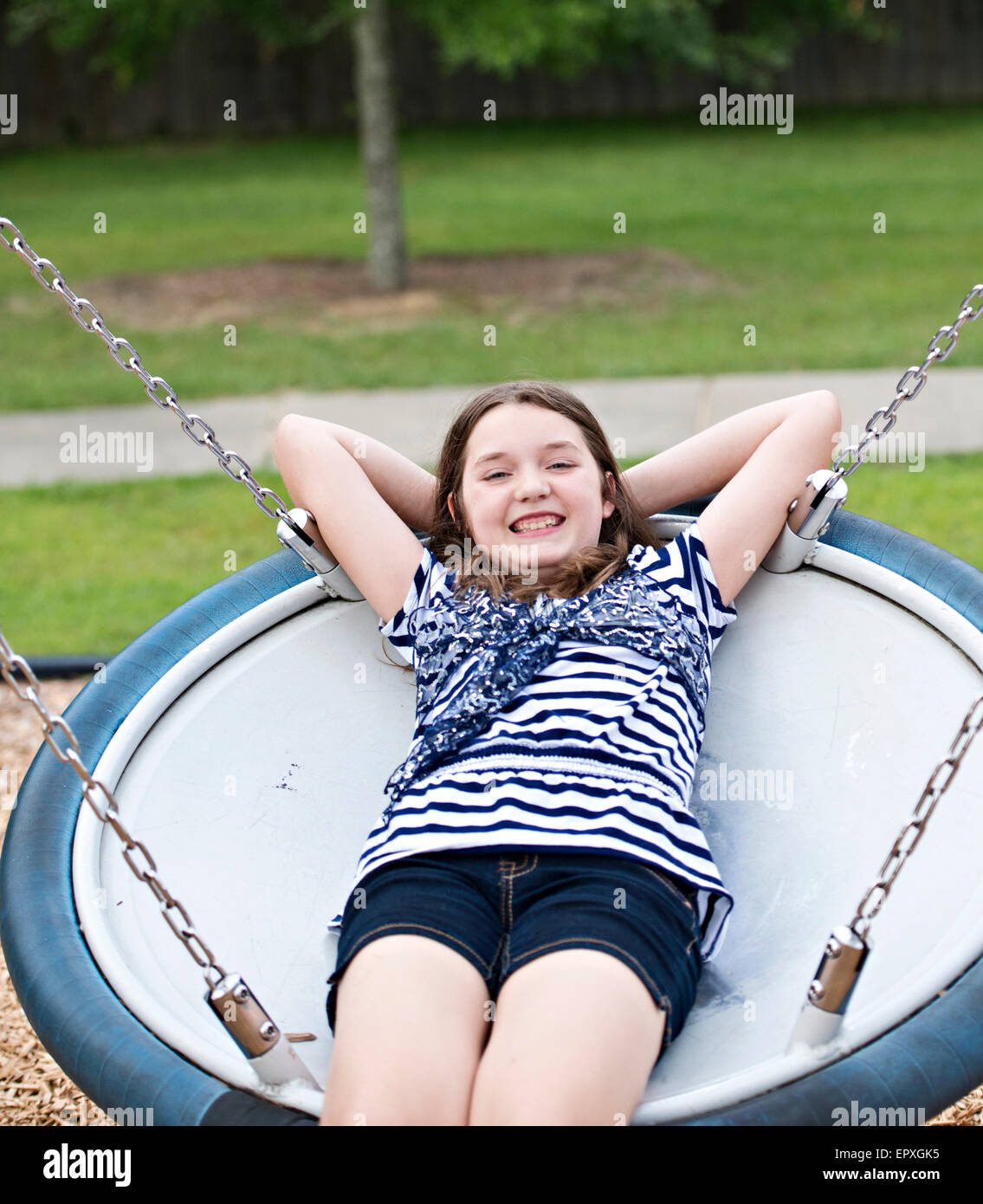 Ragazza adolescente oscilla su un piattino oscillare in un parco giochi per bambini Foto Stock