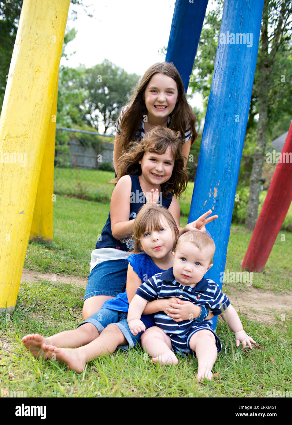 I bambini rappresentano per divertimento ritratto di famiglia in un parco all'aperto il parco giochi Foto Stock
