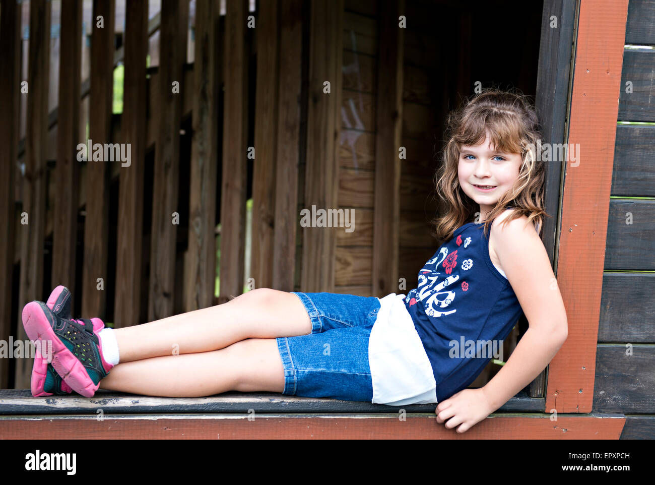 Giovane ragazza seduta in una cornice per una finestra di una piscina fort presso un parco Foto Stock