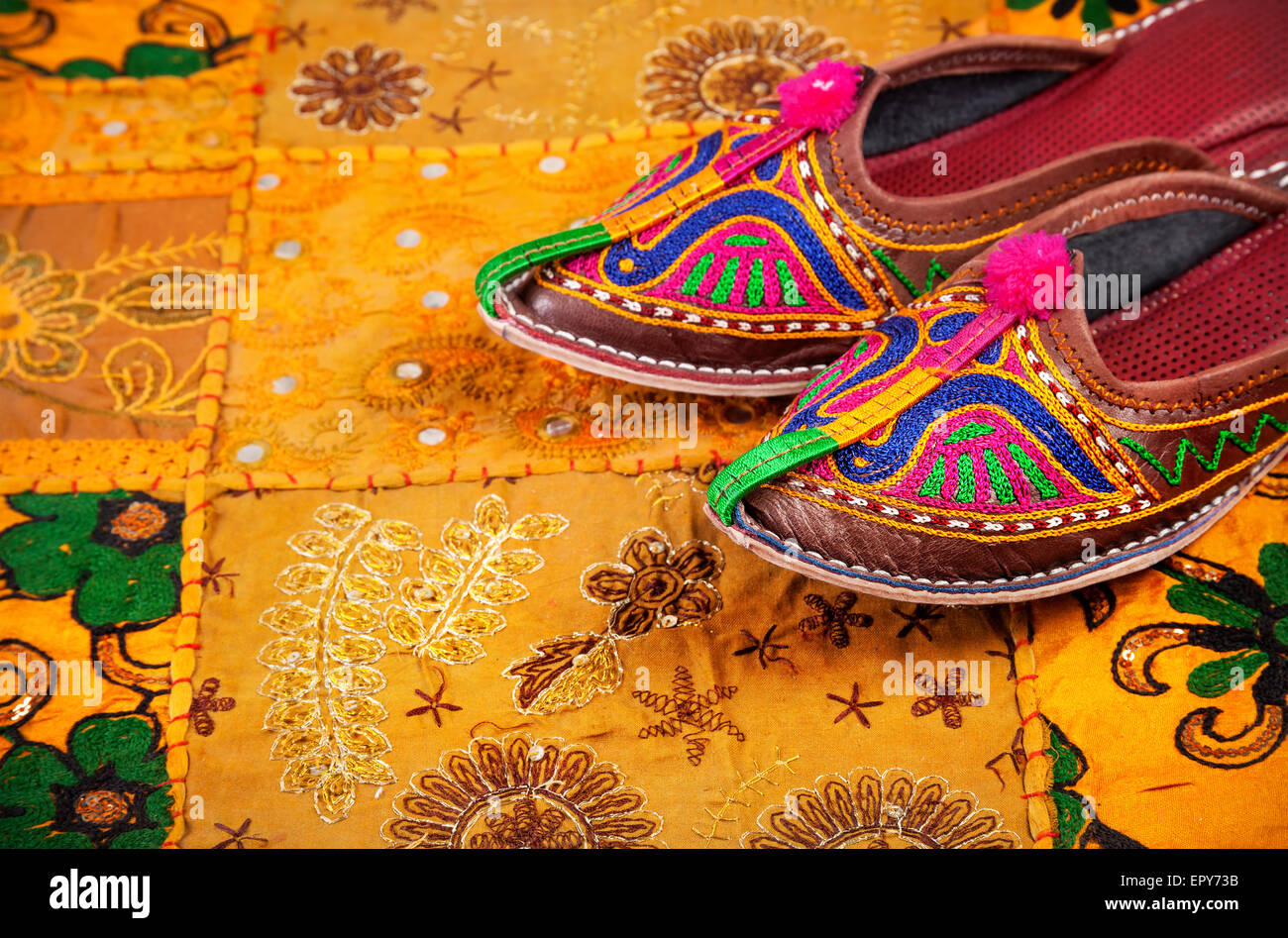 Colorate scarpe etniche su giallo Rajasthan fodera per cuscino sul mercato delle pulci in India Foto Stock