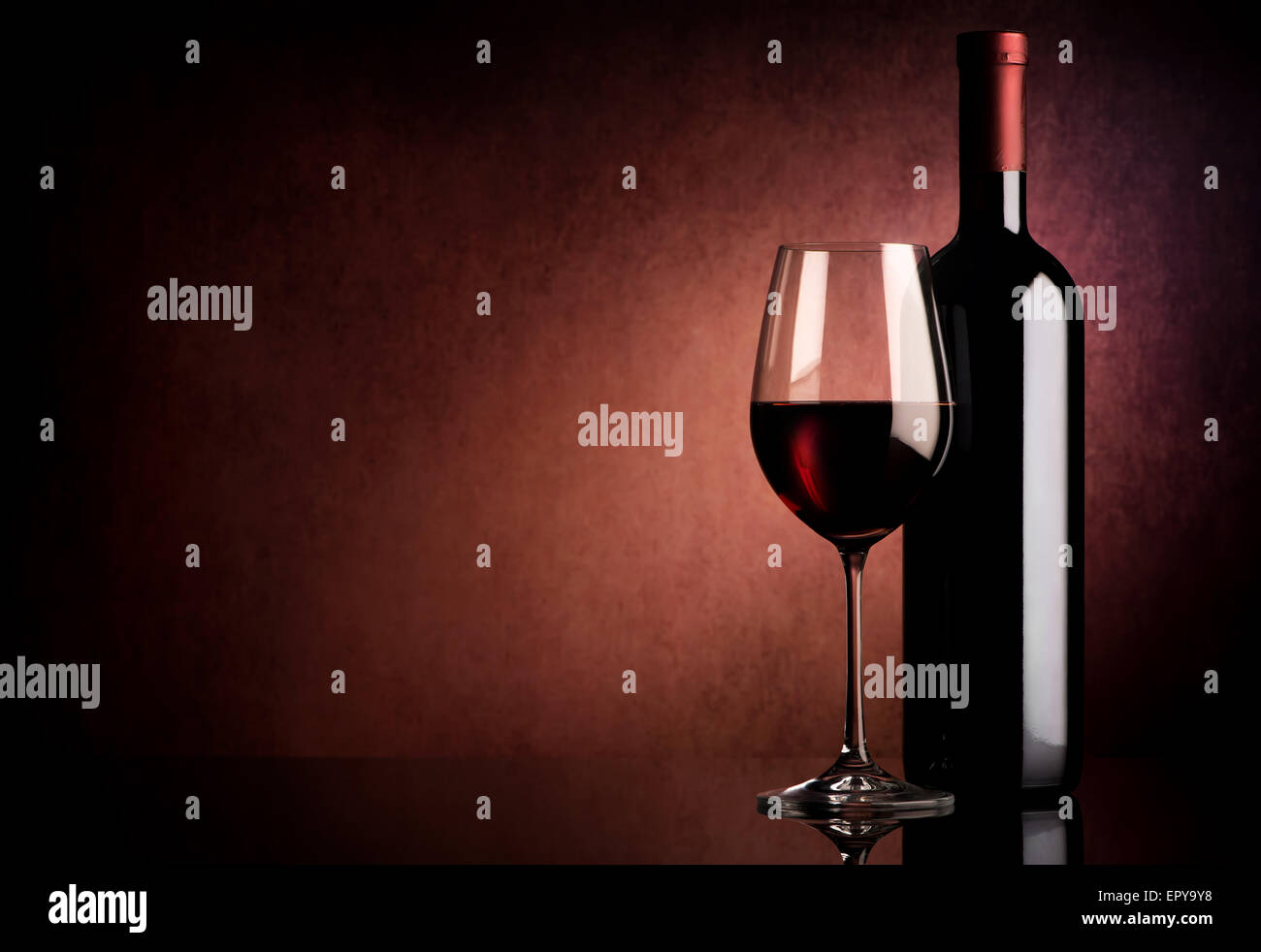 Vino rosso in bottiglia e wineglass su sfondo vinosa Foto Stock
