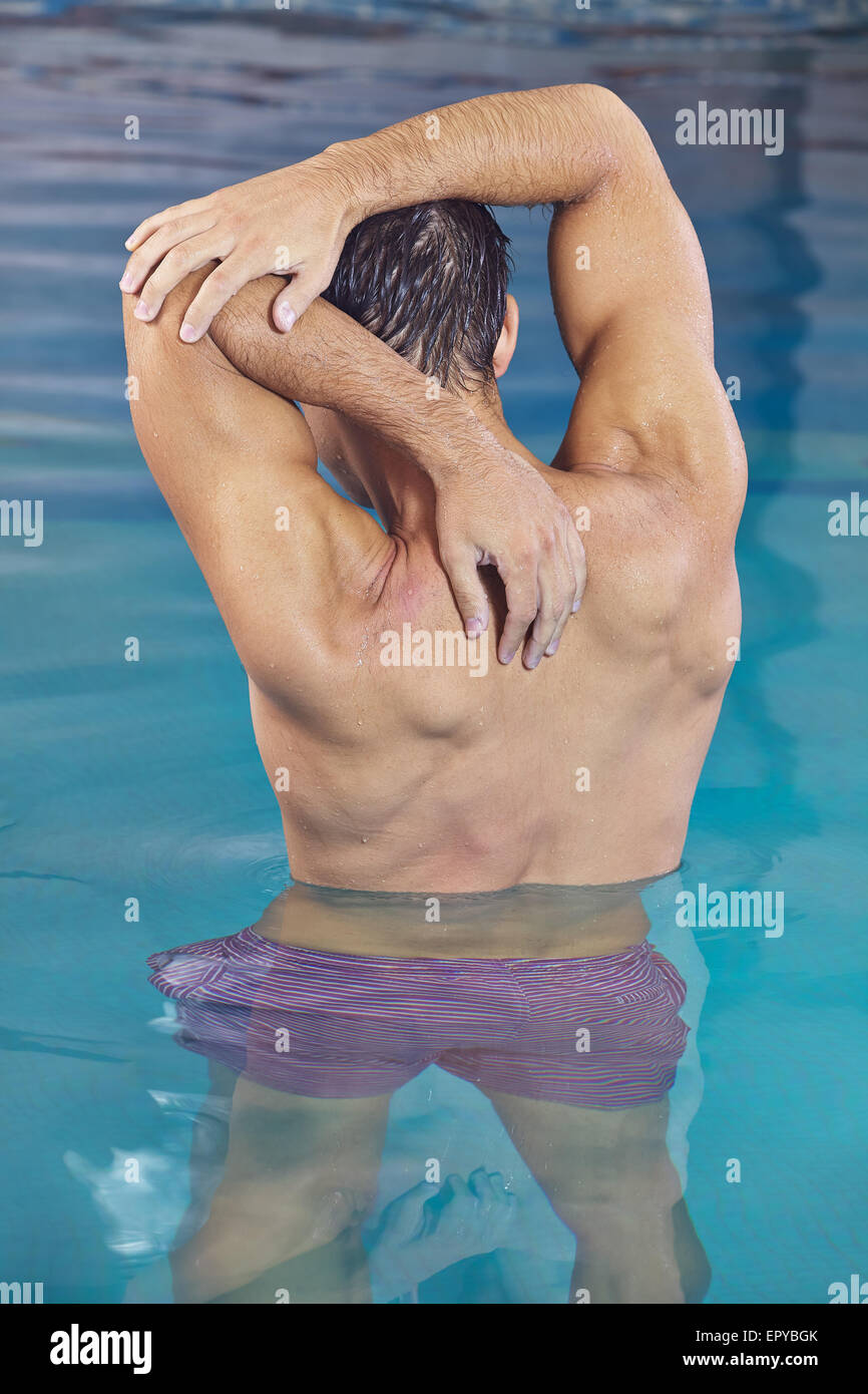 Uomo con i muscoli facendo indietro formazione in aqua fitness piscina Foto Stock