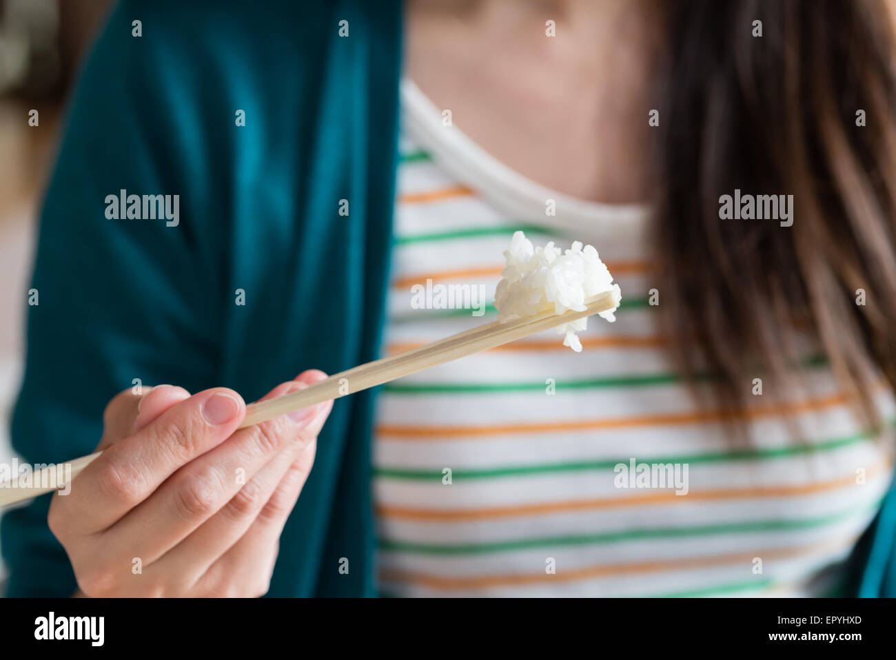 Una chiusura di una ragazza di mangiare il riso con le bacchette di legno. Foto Stock