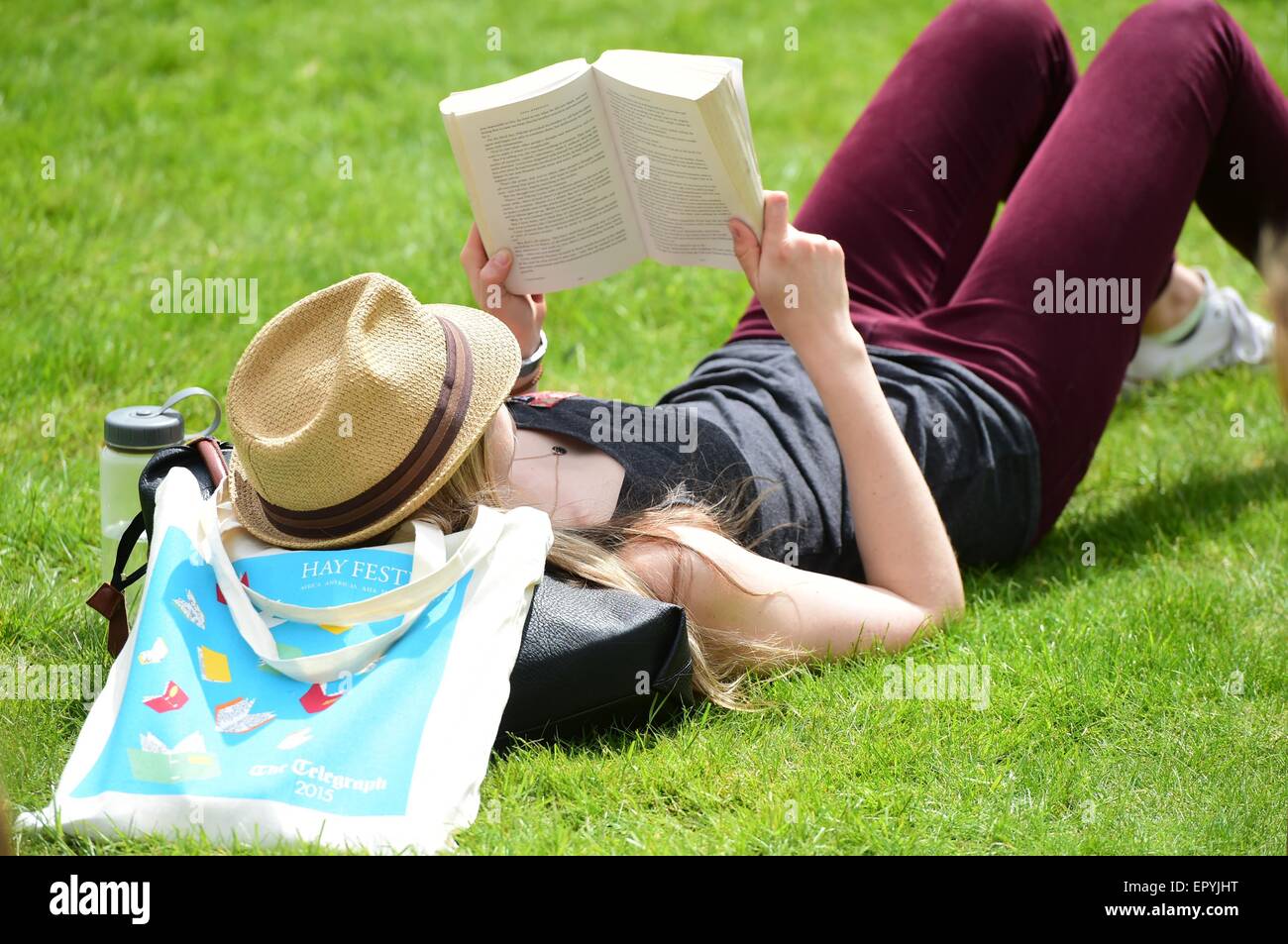 Hay on Wye. Wales UK. Sabato 23 Maggio 2015 Una giovane donna posa sull'erba la lettura di un libro in brossura godendo il sole presso la Hay Festival della Letteratura Photo credit: keith morris / Alamy Live News Foto Stock