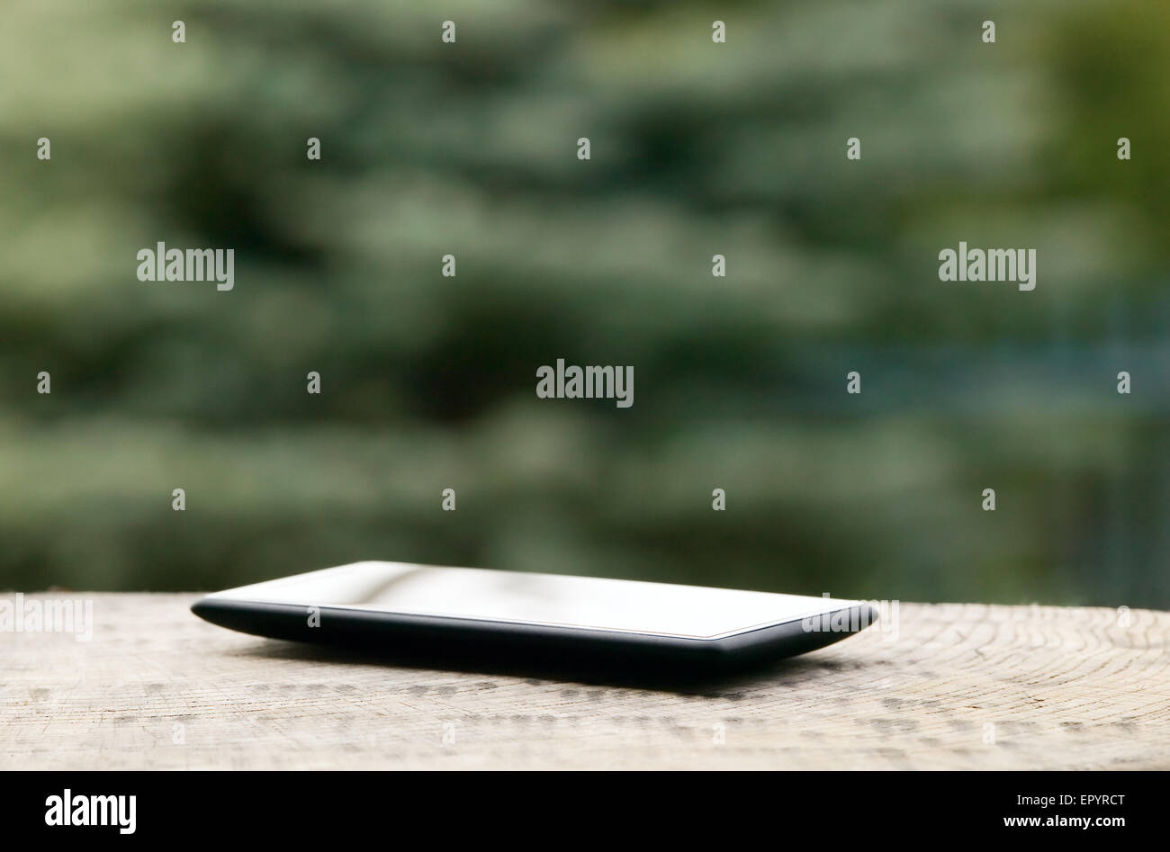 Telefono mobile collocato sul pavimento in legno con lo sfondo della natura Foto Stock