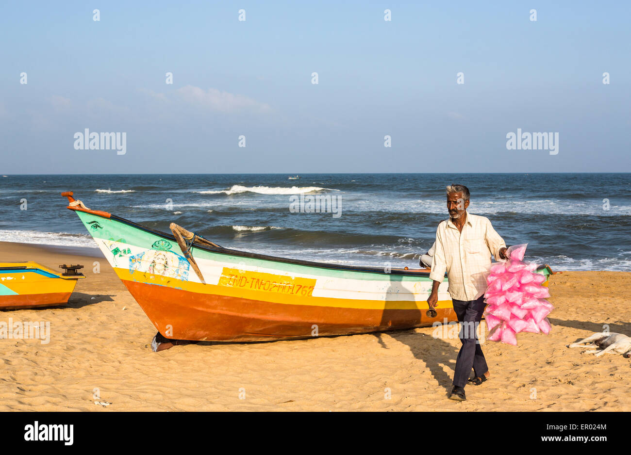 Local Candy Floss venditore sulla Marina Beach, Chennai, nello Stato del Tamil Nadu, India del sud e coloratissime barche di pescatori sulla spiaggia sabbiosa Foto Stock