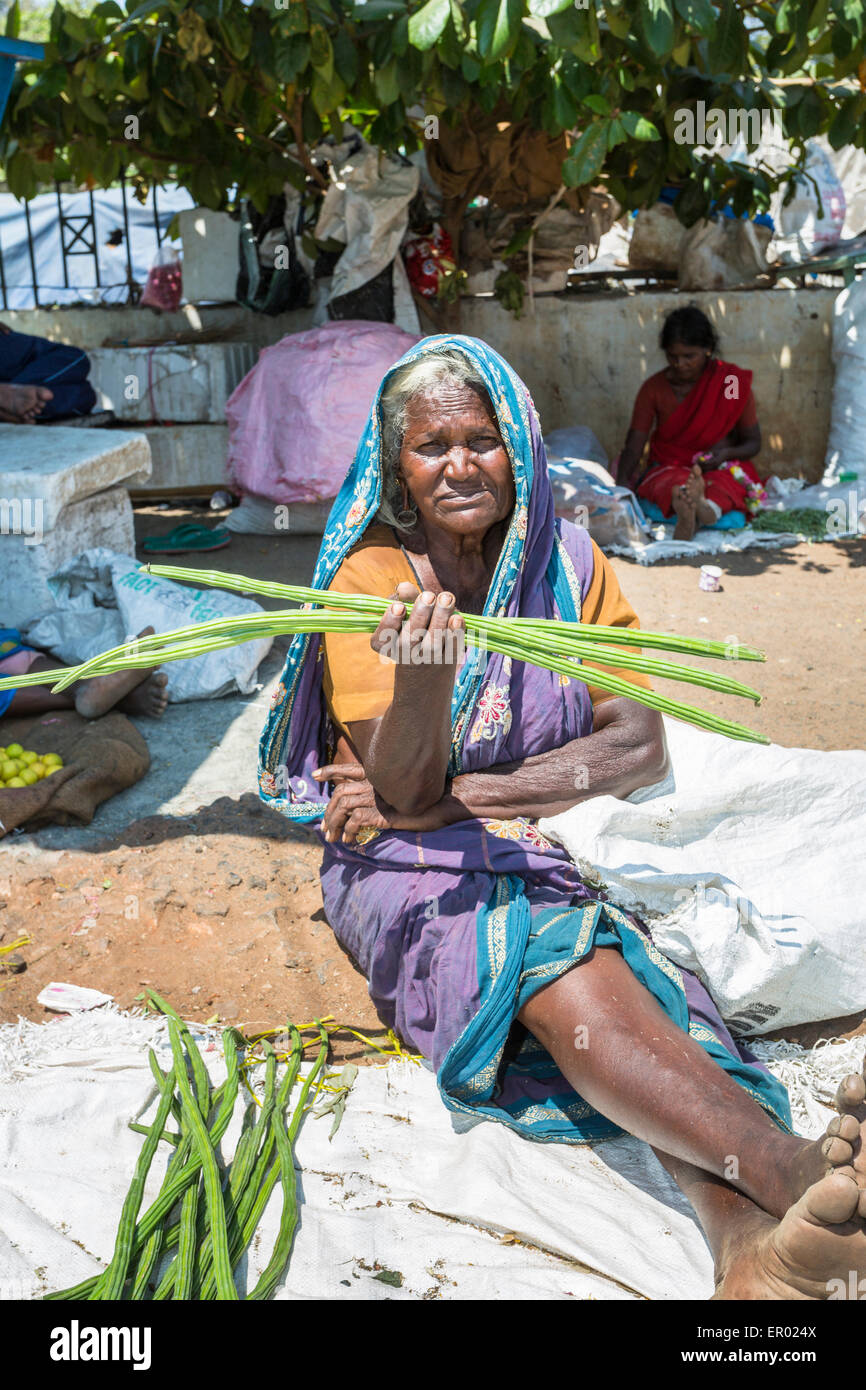Donna locale vendita di coscia tree (Moringa Oleifera) capsule di seme come verdura in un mercato a Madurai, Tamil Nadu, nell India meridionale Foto Stock