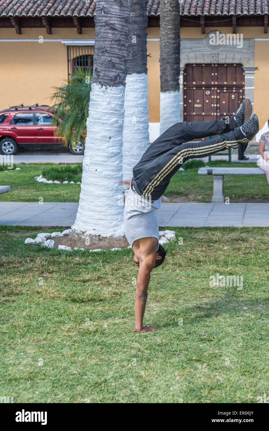 Ragazzo adolescente facendo un un braccio handstand in un parco in Antigua Guatemala Foto Stock