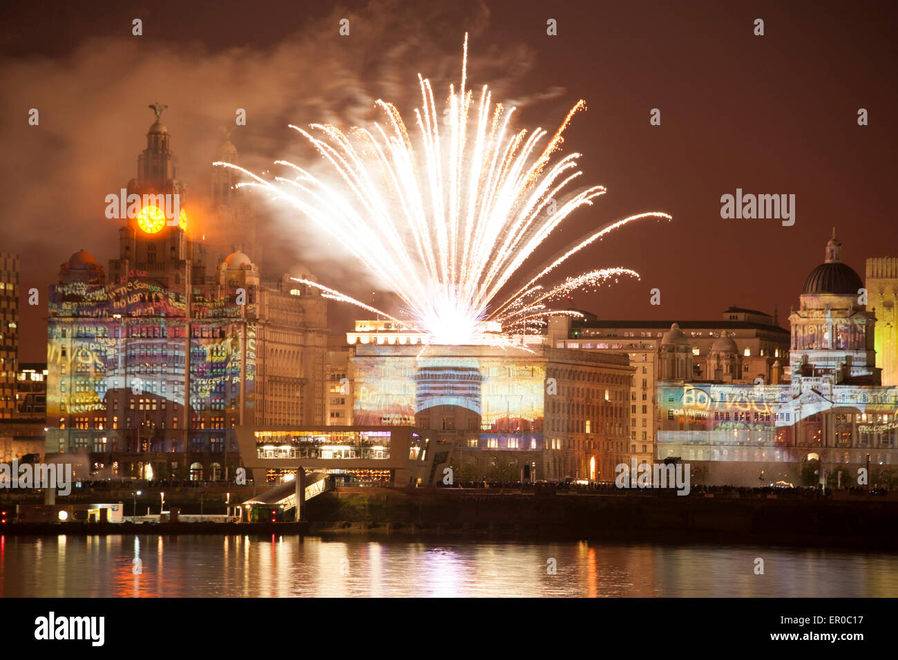 Cunard Line spedizione celebra il suo 175mo anniversario con un evento chiamato una città magnifica. Tre regine di Cunard - si tratta di tre navi - Queen Mary 2 Queen Victoria e la Queen Elizabeth vela in Liverpool insieme. La foto mostra la Cunard nave Queen Mary 2 nave contro la famosa in tutto il mondo Cunard Building, centro sul lungomare di Liverpool illuminato da fuochi d'artificio nella celebrazione. A sinistra del centro è il Royal Liver Building e alla destra del centro è il porto di Liverpool Building Foto Stock