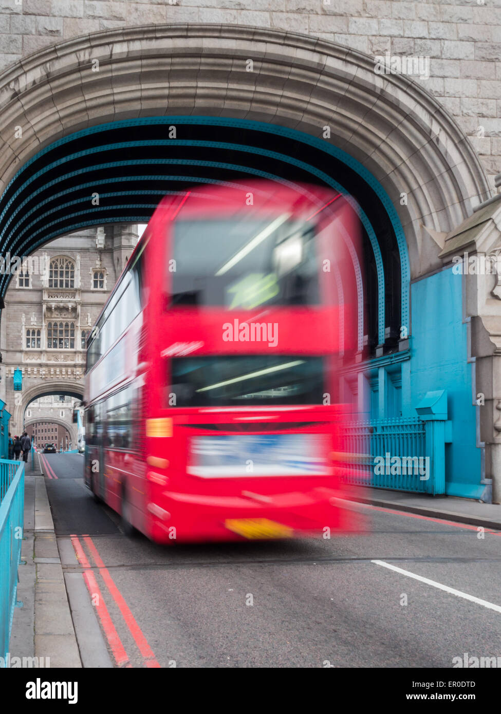 London red bus che si muove sotto il Tower Bridge arch Foto Stock