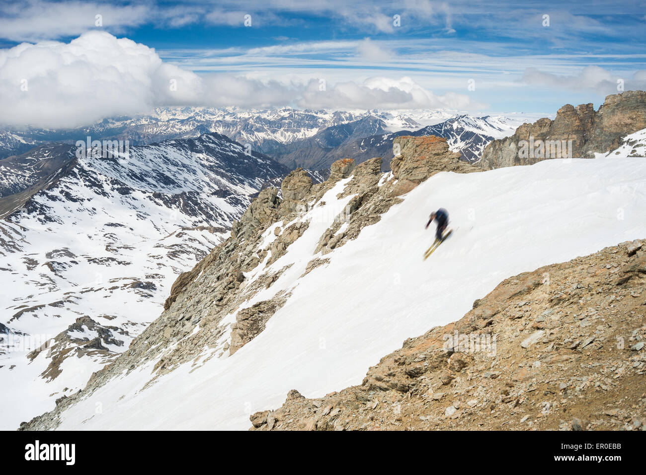 Una persona non riconoscibile sci discesa su un pendio ripido pendio nevoso. Impostazione panoramici in alta quota italiana sul sulle Alpi francesi. Foto Stock