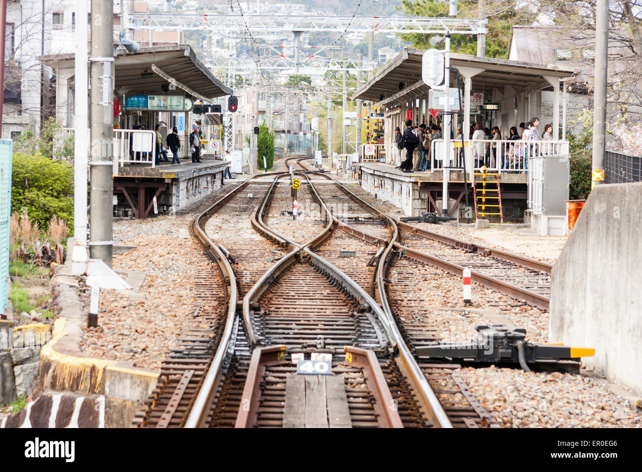 Giappone, Kurakuen. Stazione Hankyu Kurakuenguchi, con pendolari in attesa su piattaforma, distante, visto da singola linea ferroviaria che si divide in due. Foto Stock